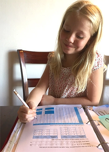 Girl filling in multiplication table from Math Mammoth page