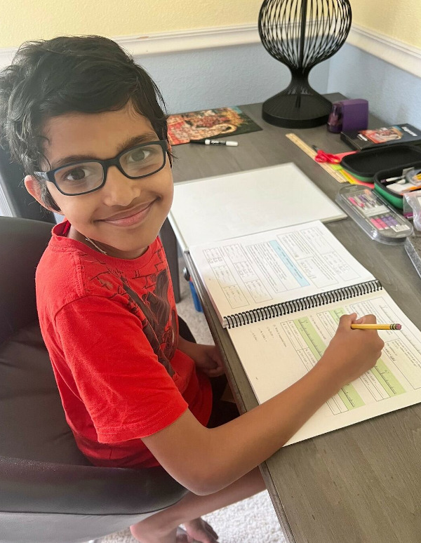 boy sitting at desk with math work, smiling