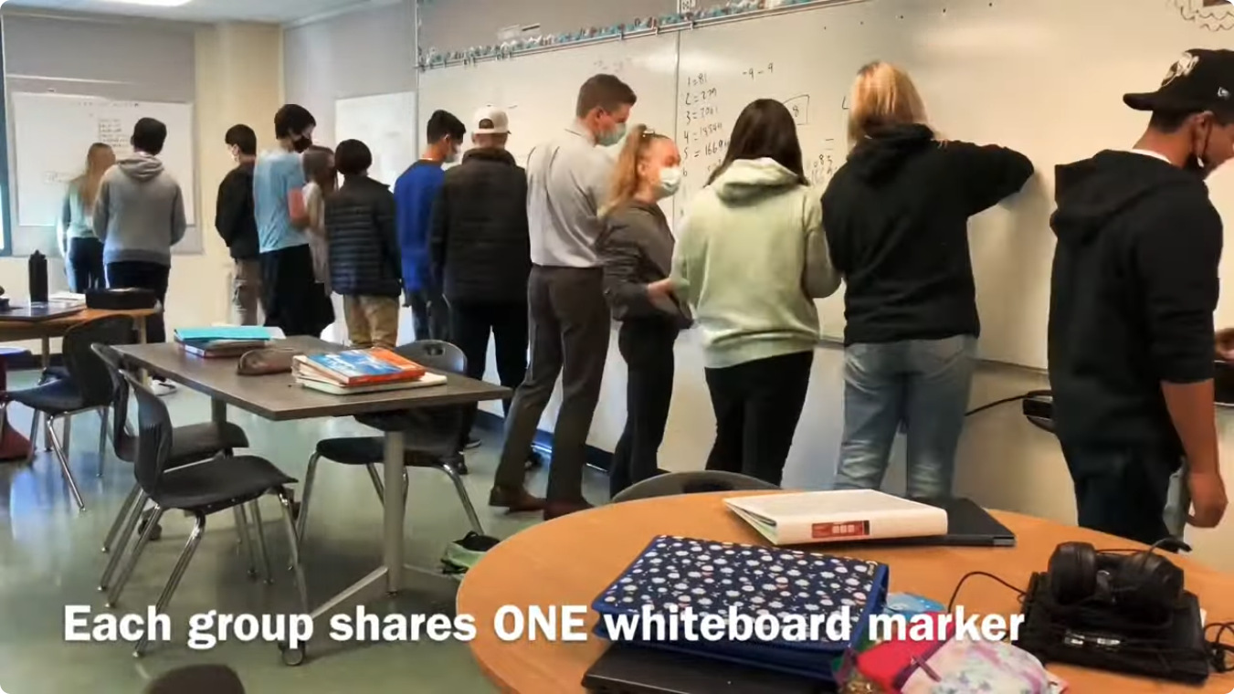 students in small groups at whiteboards